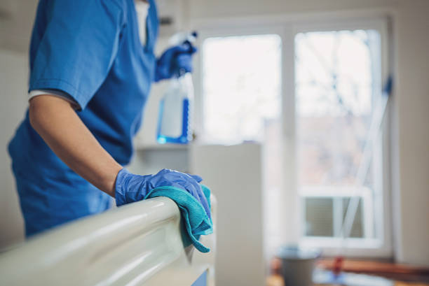 Female nurse cleaning the bed after patients in hospital ward.